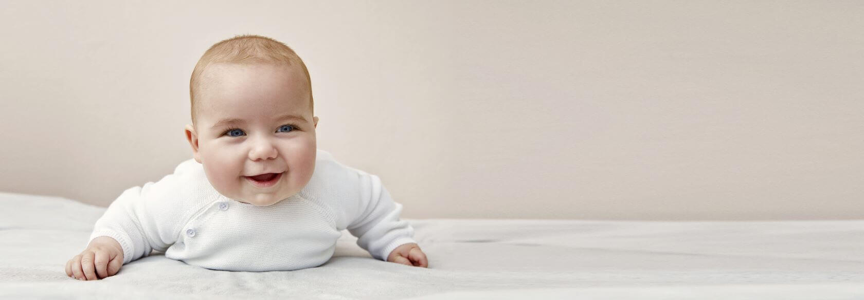 Lachende baby liggend op een witte ondergrond