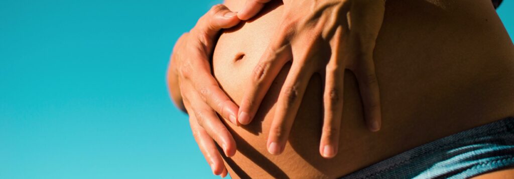 Handen die zwangere buik vasthouden
